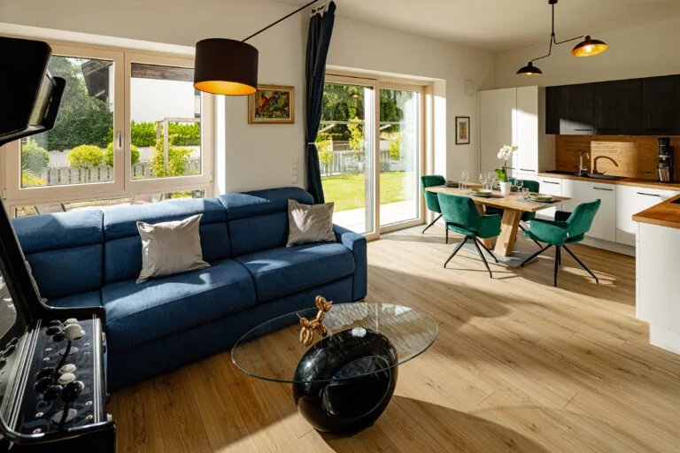 Wohnbereich mit blauem Sofa, Holztisch und grünen Sesseln