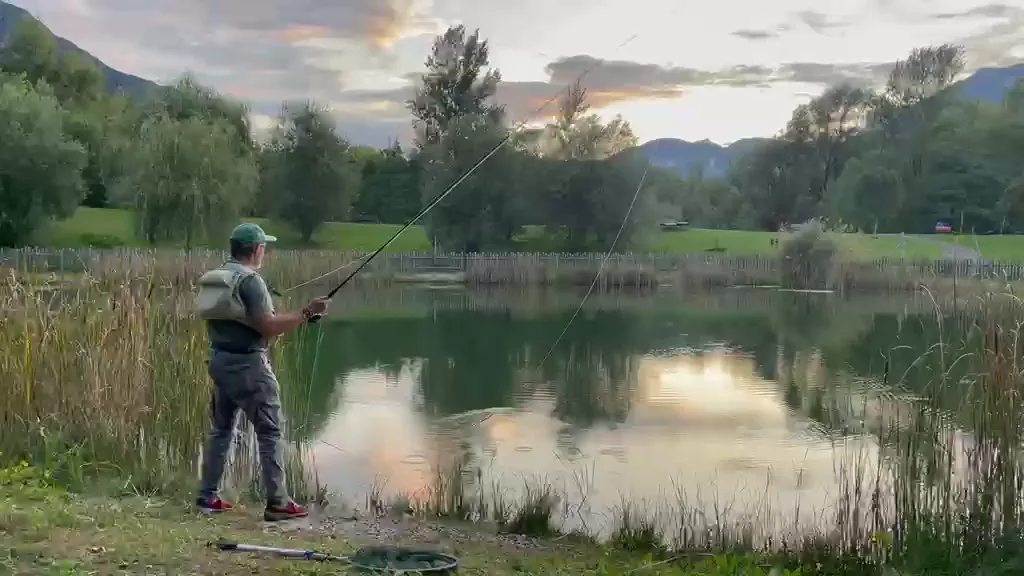 Fly fishing by the lake, with mountains and reflections in the evening light